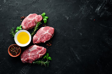 Raw steak. Meat with spices and herbs. On a black stone background. Top view. Free copy space.