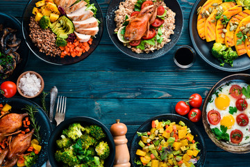 Assortment of food. Salad, avocado, quail, mushrooms, pumpkin. On a blue wooden background. Top...