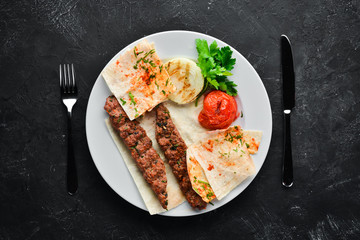 Lamb Kebab. Pita bread and spices. On a black background. Top view.