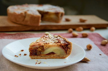 A piece of pear pie with nuts on the white plate