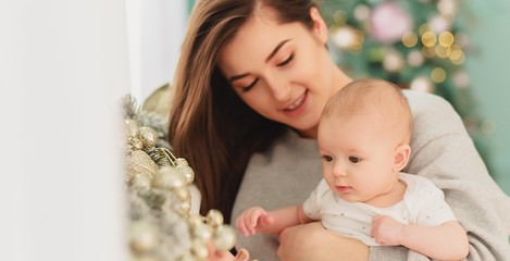 mother and her baby. A beautiful woman with dark hair and attractive facial features holds on her hands a very beautiful baby who smiles at the camera, looks at her mother is glad and happy.