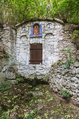 Fototapeta na wymiar The holy spring of living water, the old 17th century font, moss-covered walls, autumn. Well of holy water with spring water, well known for its healing properties