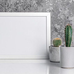 Industrial style room interior with white mockup frame and cactuses in diy concrete pots. Natural stone background and white table with reflection.