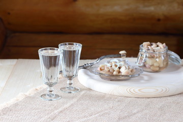 A glass of vodka and a snack from mushrooms.
