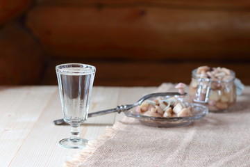 A glass of vodka and a snack from mushrooms.