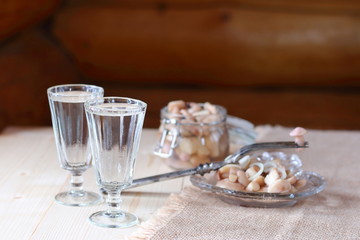 A glass of vodka and a snack from mushrooms.