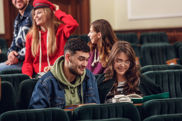 The group of cheerful students sitting in a lecture hall before lesson. The education, university, lecture, people, institute, college, studying, friendship and communication concept