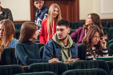 The group of cheerful students sitting in a lecture hall before lesson. The education, university, lecture, people, institute, college, studying, friendship and communication concept