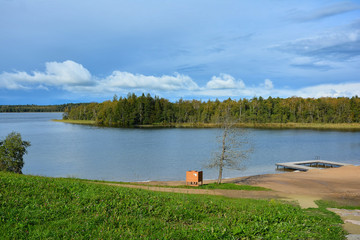 Obraz premium Blue sky, lake and forest. Beach on the lake Germantas, Lithuania. Autumn landscape on a sunny clear day.