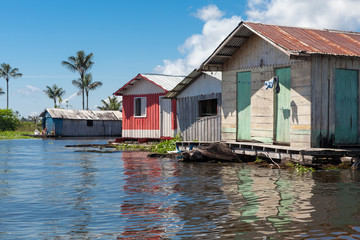 Fototapeta na wymiar Colorful wooden floating houses on the Rio Negro on sunny summer day with blue sky in the Brazilian Amazon. Manaus, Amazonas, Brazil.