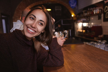 smiling cheerful woman sitting in the pub with beer