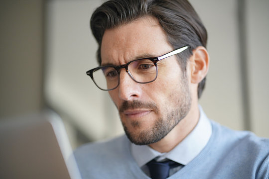 Portrait of attractive man working on laptop wearing glasses
