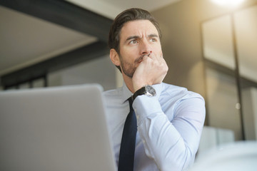 Handsome businessman in modern office looking out