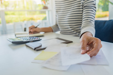 Woman with bills and calculator. Woman using calculator to calculate bills at the table in office. Calculation of costs.