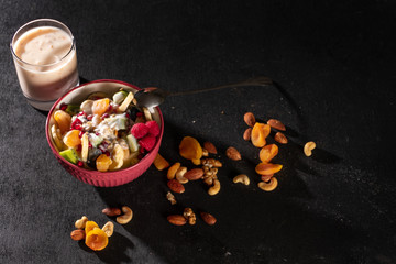 Porridge with berries and nuts in a bowl with yogurt for healthy breakfast on rustic wooden background. top view