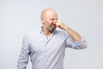 Stinky smell mature man holding nose because of bad horrible smell