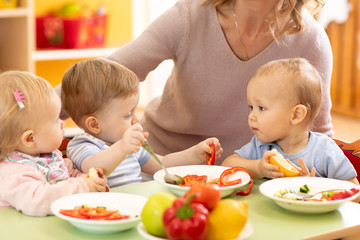 Obraz na płótnie Canvas Babies eating healthy lunch in nursery