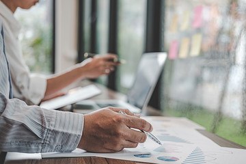 Businesswoman working at his coffee shop and using laptop, holding glasses in hand discussing the charts and graphs showing the results of their successful teamwork.