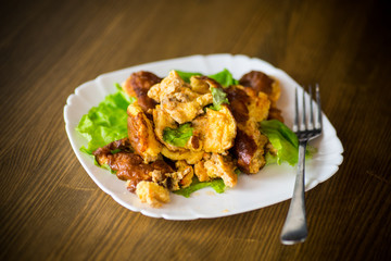 fried omelet with meat and greens in a plate