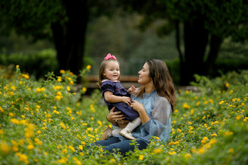 Beautiful mother and preschool toddler daughter Sitting and bonding in a yellow Flower Field