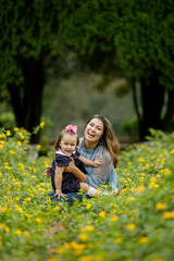 Fototapeta premium Beautiful mother and preschool toddler daughter Sitting and bonding in a yellow Flower Field