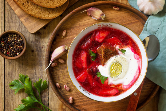 Traditional Ukrainian Russian borscht. Borsch, beetroot Soup with Sour Cream in bowl on kitchen wooden table. Top view flat lay background. Copy space.