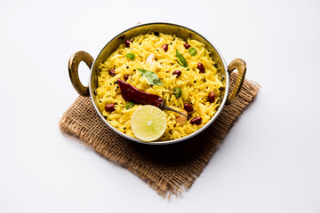 Lemon Rice is a South Indian turmeric rice or maharashtrian recipe called fodnicha bhat using leftover rice garnished with nuts curry leaves and lemon juice, selective focus