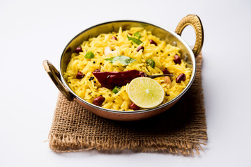 Lemon Rice is a South Indian turmeric rice or maharashtrian recipe called fodnicha bhat using leftover rice garnished with nuts curry leaves and lemon juice, selective focus