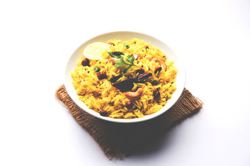 Lemon Rice is a South Indian turmeric rice or maharashtrian recipe called fodnicha bhat using leftover rice garnished with nuts curry leaves and lemon juice, selective focus