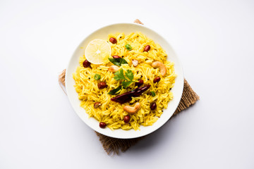 Lemon Rice is a South Indian turmeric rice or maharashtrian recipe called fodnicha bhat using leftover rice garnished with nuts curry leaves and lemon juice, selective focus