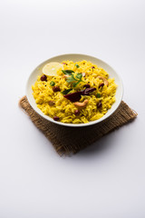 Lemon Rice is a South Indian turmeric rice or maharashtrian recipe called fodnicha bhat using leftover rice garnished with nuts curry leaves and lemon juice, selective focus
