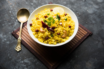 Lemon Rice is a South Indian turmeric rice or maharashtrian recipe called fodnicha bhat using leftover rice garnished with nuts curry leaves and lemon juice, selective focus