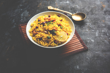 Lemon Rice is a South Indian turmeric rice or maharashtrian recipe called fodnicha bhat using leftover rice garnished with nuts curry leaves and lemon juice, selective focus