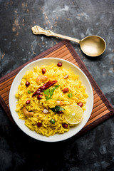 Lemon Rice is a South Indian turmeric rice or maharashtrian recipe called fodnicha bhat using leftover rice garnished with nuts curry leaves and lemon juice, selective focus
