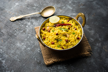 Lemon Rice is a South Indian turmeric rice or maharashtrian recipe called fodnicha bhat using leftover rice garnished with nuts curry leaves and lemon juice, selective focus