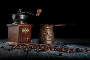 Old vintage grinder with roasted coffee beans and  turkish for coffee with wooden background. Dark still life