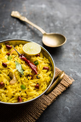 Lemon Rice is a South Indian turmeric rice or maharashtrian recipe called fodnicha bhat using leftover rice garnished with nuts curry leaves and lemon juice, selective focus