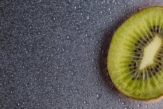 Kiwi closeup on a gray background with drops of water