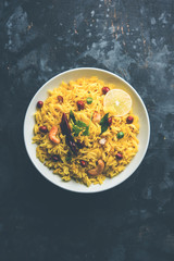 Lemon Rice is a South Indian turmeric rice or maharashtrian recipe called fodnicha bhat using leftover rice garnished with nuts curry leaves and lemon juice, selective focus