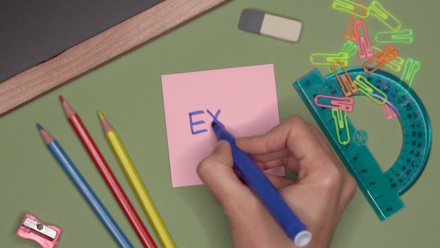 School concept. Womans hand writing EXAM on notepad