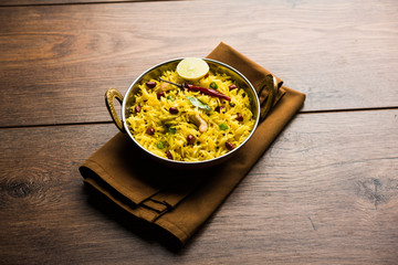 Lemon Rice is a South Indian turmeric rice or maharashtrian recipe called fodnicha bhat using leftover rice garnished with nuts curry leaves and lemon juice, selective focus