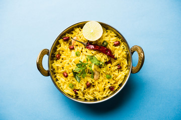 Lemon Rice is a South Indian turmeric rice or maharashtrian recipe called fodnicha bhat using leftover rice garnished with nuts curry leaves and lemon juice, selective focus