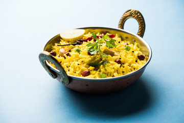 Lemon Rice is a South Indian turmeric rice or maharashtrian recipe called fodnicha bhat using leftover rice garnished with nuts curry leaves and lemon juice, selective focus