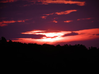 Red sunset with clouds and sunlight getting through the clouds