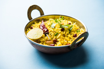 Lemon Rice is a South Indian turmeric rice or maharashtrian recipe called fodnicha bhat using leftover rice garnished with nuts curry leaves and lemon juice, selective focus