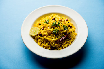 Lemon Rice is a South Indian turmeric rice or maharashtrian recipe called fodnicha bhat using leftover rice garnished with nuts curry leaves and lemon juice, selective focus