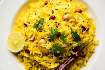 Lemon Rice is a South Indian turmeric rice or maharashtrian recipe called fodnicha bhat using leftover rice garnished with nuts curry leaves and lemon juice, selective focus