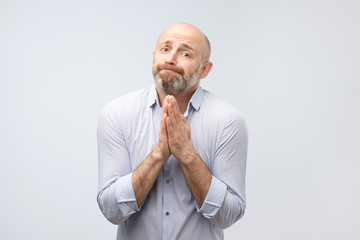 Please help me now. Bearded mature man need a help. Isolated on gray background, studio shot