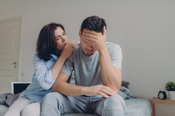 Attractive female consoles her sad boyfriend who has depression and some problems, pose at bedroom...