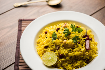 Lemon Rice is a South Indian turmeric rice or maharashtrian recipe called fodnicha bhat using leftover rice garnished with nuts curry leaves and lemon juice, selective focus